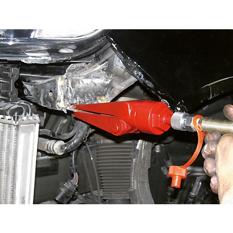 Nahaufnahme eines roten Werkzeugs, das an einem Autoteil eingesetzt wird, um es zu reparieren.